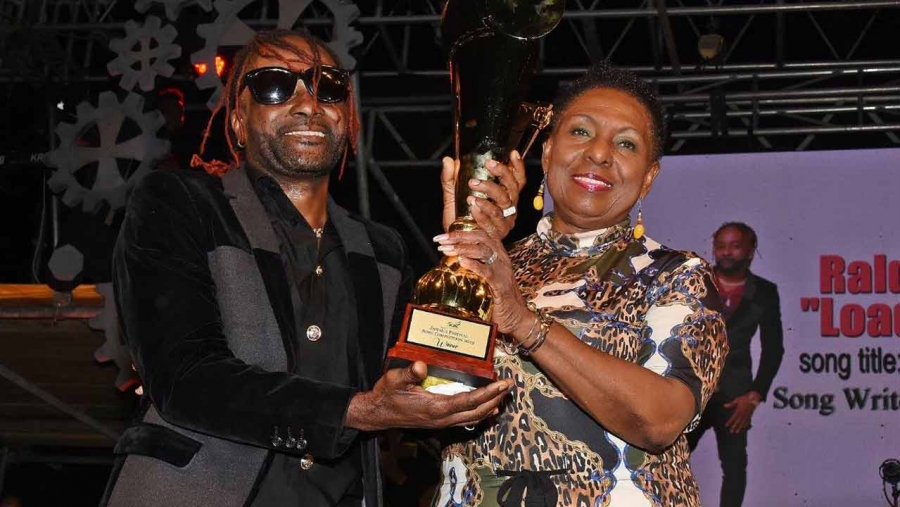 The Minister of Culture, Gender, Entertainment and Sport, the Honourable Olivia Grange presents trophy to Jamaica Festival Song Winner 2019, Raldene 'Loaded Eagle' Dyer