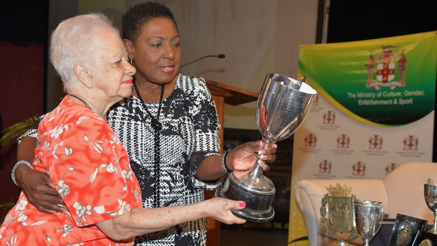 The Minister of Culture Gender, Entertainment and Sport, the Honourable Olivia Grange (right) accepts donations for the National Sport Museum from former hockey player and administrator, Kay Wilson.