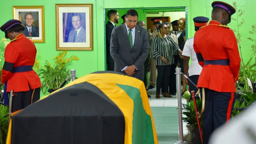 The Most Honourable Andrew Holness and behind him is the  Minister of Culture, Gender, Entertainment and Sport, The Honourable Olivia Grange paying their respects at the Jamaica Labour Party head office.