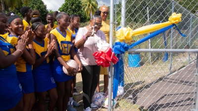 The Minister of Culture, Gender, Entertainment and Sport, the Honourable Olivia Grange (centre) opens the new multi-sport facility at Papine High School on Friday (December 9, 2022).  The new court was built for netball, volleyball and basketball and was constructed by the Sports Development Foundation.  Sharing the moment are the Minister of Education and Youth, the Honourable Fayval Williams (right) and students from the school.