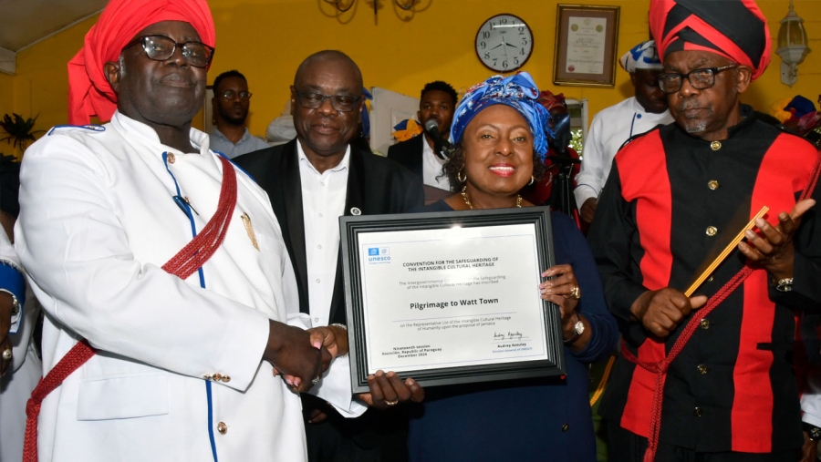 The Minister of Culture, Gender, Entertainment and Sport, the Honourable Olivia Grange presents the certificate of inscription to Bishop Robert Clark in Watt Town, St Ann on 6 March 2025. The Revival ‘Pilgrimage To Watt Town’ was inscribed to the UNESCO list of Intangible Cultural Heritage in December 2024. Also pictured is Councillor Cardel Wickham, Deputy Mayor of St Ann&#039;s Bay (2nd left) and Bishop Guthrie (right).