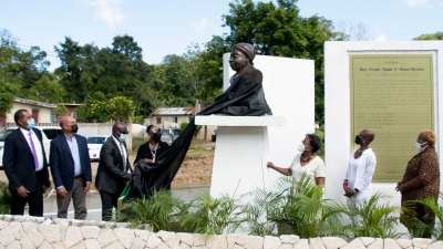The Minister of Culture, Gender, Entertainment and Sport, the Honourable Olivia Grange, unveils the monument to supercentenarian Violet Moss Brown in Duanvale, Trelawny on Thursday, 10 March 2022.  The Minister is assisted by the Mayor of Falmouth, His Worship Collen Gager (3rd left).  Also sharing the moment are (from left to right) Councillor for the Sherwood Content Division, Dunstan Harper; Custos of Trelawny, the Honourable Hugh Gentles; Sculptor, Pamrie Hall Dwyer; and Dr Beverly Davis Fray and Lelieth Palmer, granddaughters of Mrs Moss Brown.