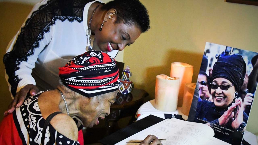 The Minister of Culture, Gender, Entertainment and Sport, the Honourable Olivia Grange, with Queen Mother Marianne Samad (seated) at the signing of a Book of Condolence for South African Activist, Winnie Mandela.