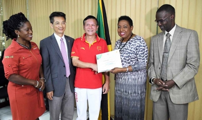 The Honourable Olivia Grange, Minister of Culture, Gender, Entertainment and Sport presents a Certificate of Appreciation to Zou Zhengqiu, Chinese Gymnastics Coach for his role in the Technical Agreement on Sport between Jamaica and the People’s Republic of China. The team of seven coaches in the areas of swimming, synchronised swimming, badminton, gymnastics, volleyball, football and basketball for females will depart the island tomorrow, February 9. Sharing in the moment were: Denzil Thorpe, Permanent Secretary in the Ministry (right); Jianhong Fan, Counsellor, The Embassy of the People’s Republic of China in Jamaica (second left) and Nicole Grant-Brown, President, Jamaica Amateur Gymnastics Association (left).