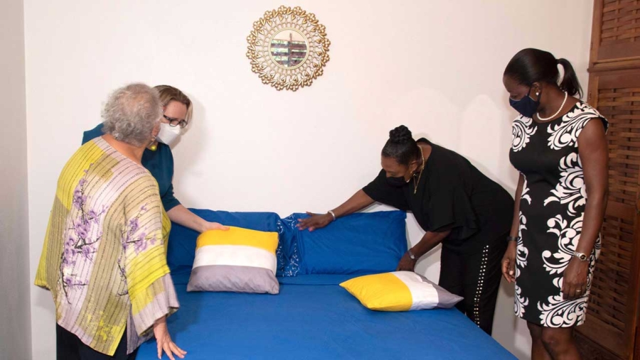 Minister of Culture, Gender, Entertainment and Sport, the Honourable Olivia Grange (2nd right), fluffs a pillow during a tour and opening of the second government-run shelter for women victims of domestic abuse. Sharing the moment are (l-r) Director of the UNFPA Caribbean Office, Alyson Drayton; the High Commissioner of Canada, Her Excellency Emina Tudakovic (partially hidden); and Programme Manager of the European Union Delegation to Jamaica, Vanna Lawrence.