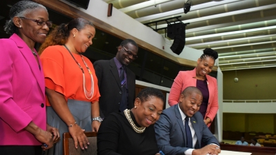 The Minister of Culture, Gender, Entertainment and Sport, the Honourable Olivia Grange (seated left) and the Minister of State in the Ministry of Education, Youth and Information, the Honourable Floyd Green sign a Letter of Commitment towards the implementation of ‘The Policy for the Reintegration of School-Age Mothers into the Formal School System’. The signing took place at a Stakeholders’ Forum organised by the Women’s Centre of Jamaica Foundation at the Jamaica Conference Centre on Thursday. Looking on are: Dr Zoe Simpson, Executive Director, Women’s Centre of Jamaica Foundation; Debby-Ann Brown-Salmon, Chairman, WCJF; Denzil Thorpe; Permanent Secretary in the Ministry of Culture, Gender, Entertainment and Sport and Dasmine Kennedy, Deputy Chief Education Officer (Acting) Schools Operations, Ministry of Education, Youth and Information (left to right).