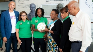 Minister of Culture, Gender, Entertainment and Sport, the Honourable Olivia Grange (3rd right), receives from Reggae Girlz captain Konya Plummer a football signed by members of the team. The Reggae Girlz departed Jamaica on Monday to begin final preparation for the FIFA Women's World Cup in France. Sharing the moment are JFF President, Michael Ricketts (r) and from Caribbean Airlines: Zachary Harding, Director; Alicia Cabrera, Senior Marketing Manager; and Trudy Chin, General Manager.