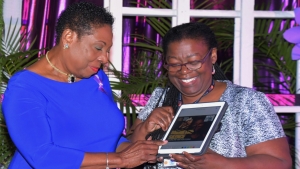 The Minister of Culture, Gender, Entertainment and Sport, the Honourable Olivia Grange signs the online gender-based violence platform. Also photographed is Vilma Gregory, Advocacy and Communications Consultant, UNFPA Caribbean Sub-Region Office (right).