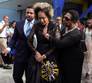 The Honourable Olivia Grange, Minister of Culture, Gender, Entertainment and Sport consoles Kelly-Ann Boyne, daughter of the late Ian Boyne as she and her brother Andre Skeen (left) depart the National Indoor Sports Centre where the Thanksgiving Service for the life of their father was held today (Sunday).