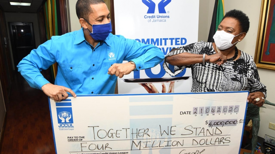 The Minister of Culture, Gender, Entertainment and Sport, the Honourable Olivia Grange (right) does an elbow bump with the Group Chief Executive Officer of the Jamaica Co-operative Credit Union League, Mr Robin Levy as he presents her with a symbolic cheque of the JCCUL&#039;s J$4M contribution to Telethon Jamaica: Together We Stand. The six hour, virtual telethon raised funds to provide Jamaica’s frontline workers with equipment to battle Covid-19.
