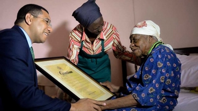 Prime Minister, the Most Honourable Andrew Holness (left) visits supercentenarian Violet Moss-Brown in 2017