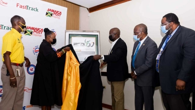 The Minister of Culture, Gender, Entertainment and Sport, the Honourable Olivia Grange (second left) unveils the Jamaica 60th Independence anniversary stamp with the assistance of the Chairman of the Board of Directors of the Postal Corporation of Jamaica, Professor Felix Akinladejo (third right). They are also joined by the Permanent Secretary, Denzil Thorpe (left) and Senior Director of Corporate Services of the Post and Telecommunications Department, Herbert Fletcher (second right), and the Director of Post and Telecommunications in the Ministry of Science, Energy and Technology, Cecil McCain.