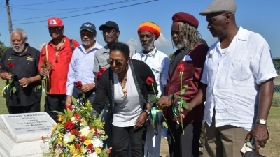 Minister of Culture, Gender, Entertainment and Sport, the Honourable Olivia Grange makes a Floral Tribute at the resting place of Dennis Brown (National Heroes Park) on the anniversary of his 62nd birthday and as part of activities to celebrate Reggae Month. Also photographed are: Ibo Cooper, Chairman, Jamaica Reggae Industry Association; Copeland Forbes, producer/manager; Junior Lincoln, producer/manager; Lloyd Parks, band leader/reggae vocalist; Sangie Davis, musician; Trevor &#039;Leggo&#039; Douglas, owner of Leggo Records and Paul ‘Jah Screw&#039; Love, producer/musician (left to right).