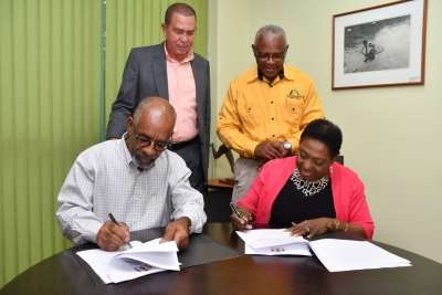The Honourable Olivia Grange, Minister of Culture, Gender, Entertainment and Sport signs an agreement with Sculptor, Basil Watson (left) to begin work on the statues for Veronica Campbell-Brown and Asafa Powell. Looking on are: Lloyd ‘Bunny’ Pommells, Deputy Chairman, Sports Development Foundation and Major Desmon Brown, General Manager, Independence Park Limited (standing from left). The agreements were signed at the Ministry’s Trafalgar Road offices on Wednesday.