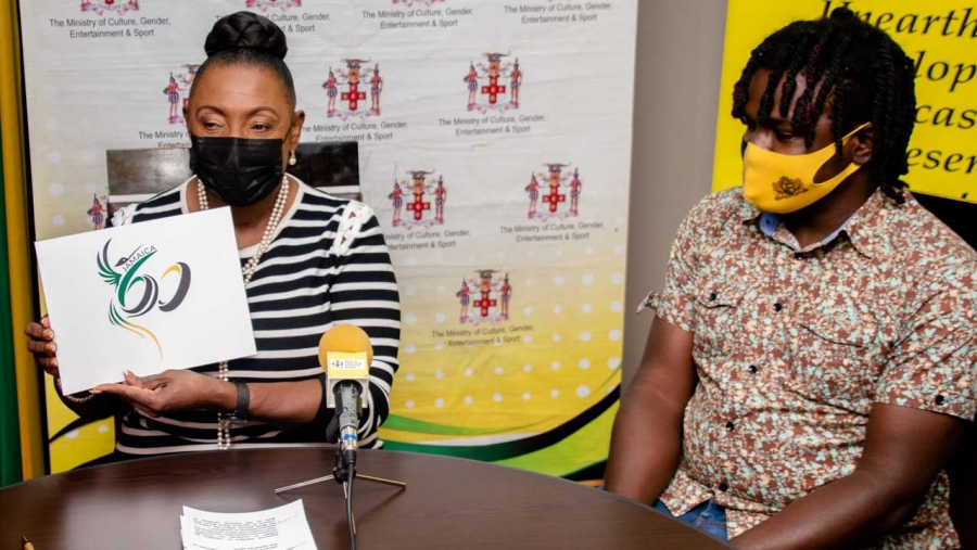 The Minister of Culture, Gender, Entertainment and Sport, the Honourable Olivia Grange, holds up the winning entry in the Jamaica 60 logo design competition.  The designer, Bobby Smith, looks on.